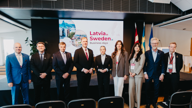 Oficiālās vizītes dalībnieku kopbilde, kur fonā redzama prezentācija "Latvia Sweden"