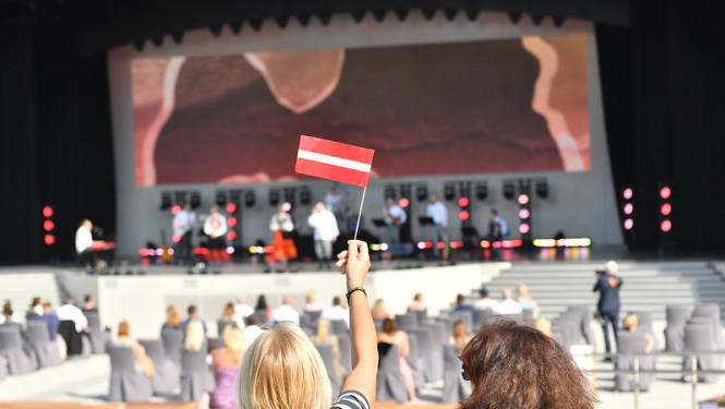 sieviete tur rokā Latvijas karogu