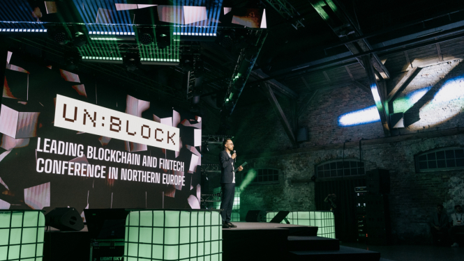 Konferences Unblock 2026 skatuve, uz kuras redzams vadītājs