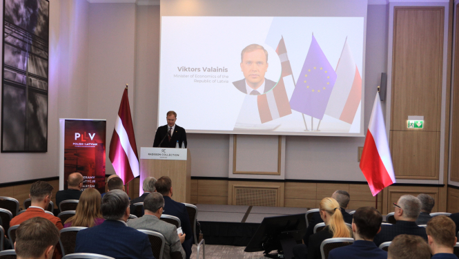 Uz skatuves ekonomikas ministrs Viktors Valainis. Balkus skatuvei labajā malā Polijas karogs, kreisajā malā Latvijas karogs. 