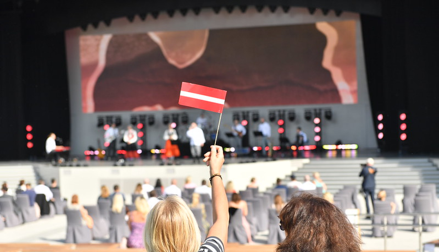 sieviete tur rokā Latvijas karogu