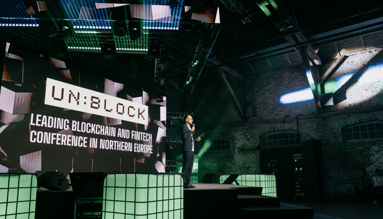 Konferences Unblock 2026 skatuve, uz kuras redzams vadītājs