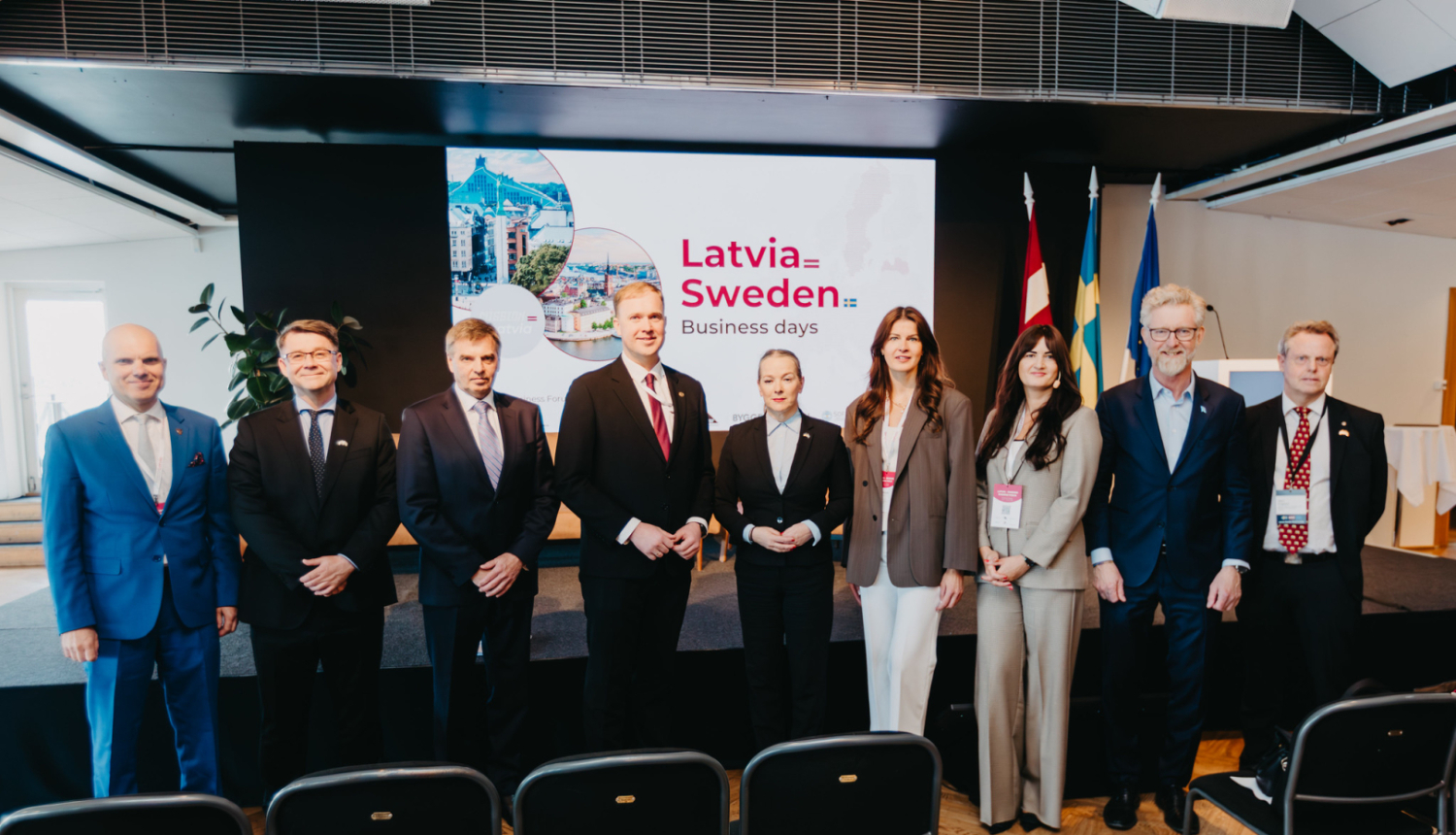 Oficiālās vizītes dalībnieku kopbilde, kur fonā redzama prezentācija "Latvia Sweden"